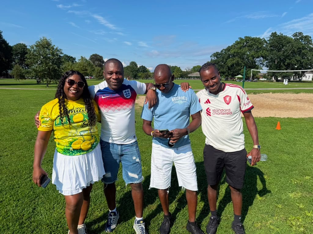 Four Friends of Porus supporters in football jerseys smiling on the field at the picnic